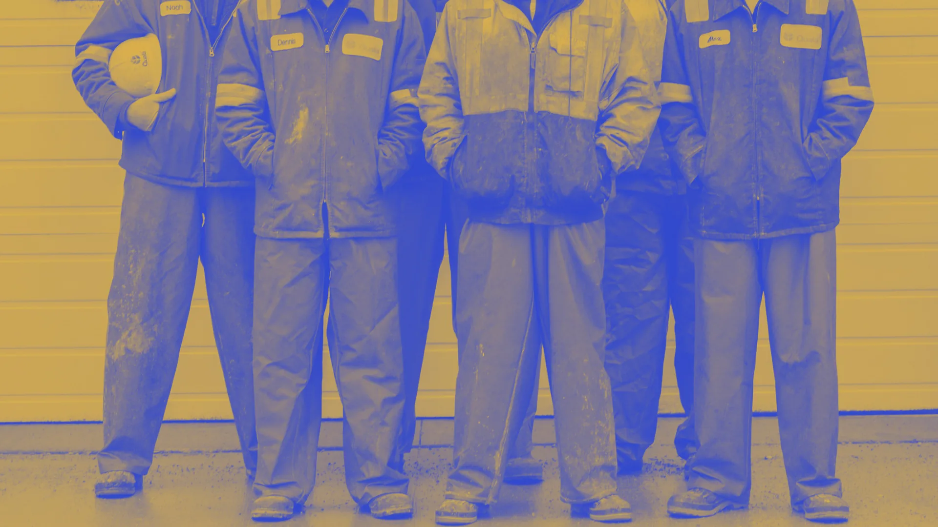 Squadra di operai in tuta da lavoro schierata davanti al capannone