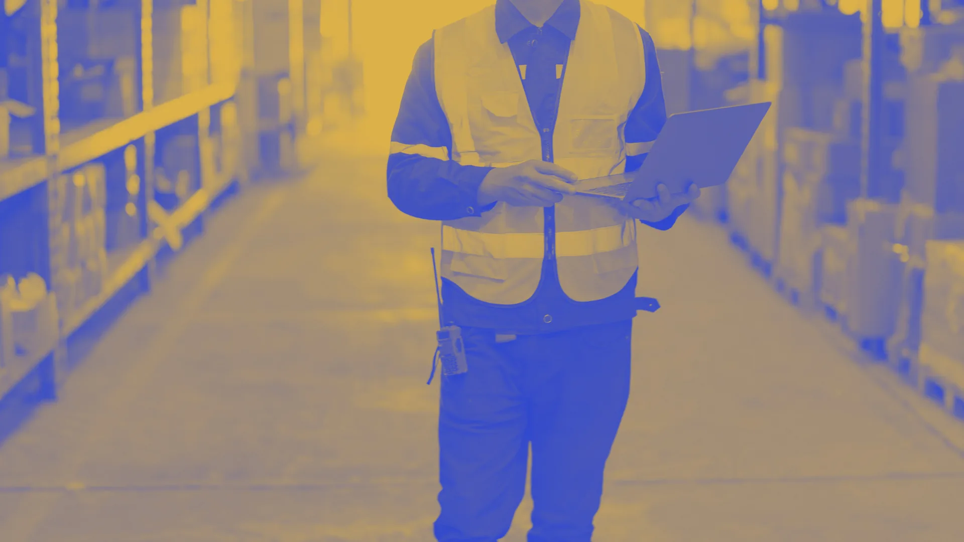 Addetto con giubbotto ad alta visibilità e portatile fra gli scaffali di un magazzino